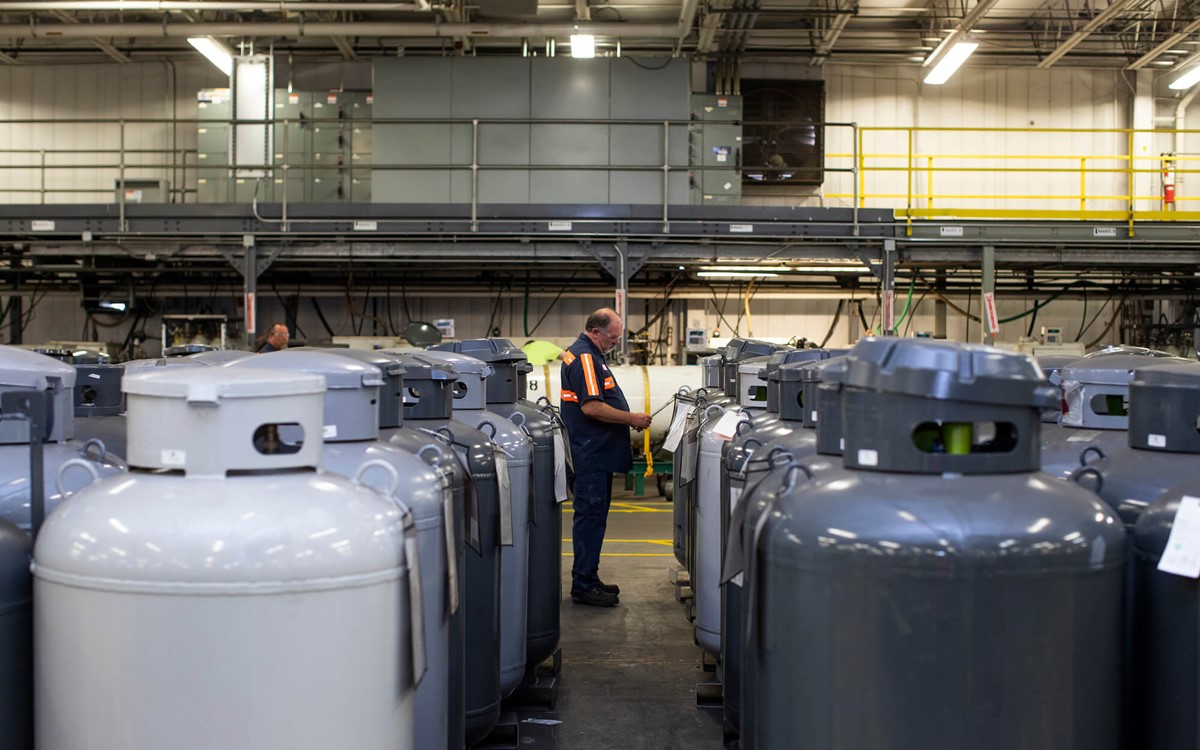 A person stood in between two rows of industrial gas cylinders