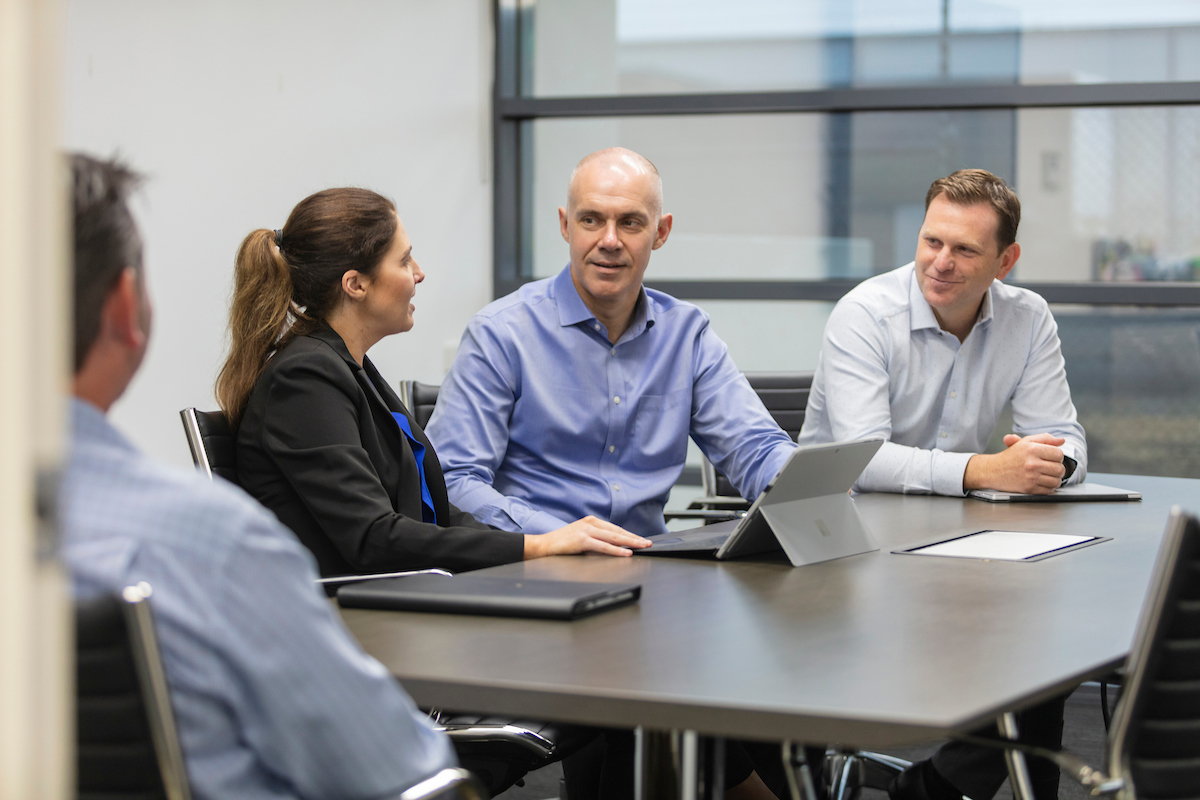 A woman and two men talking in a meeting 