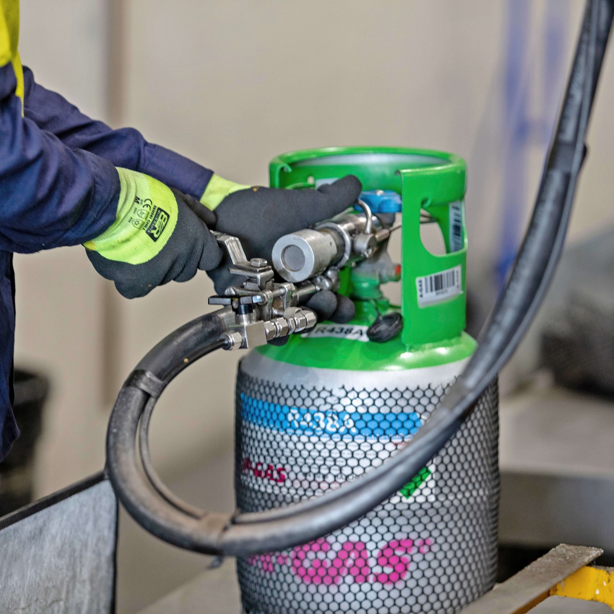 Close-up of engineer working with a hose on a green-topped gas cylinder