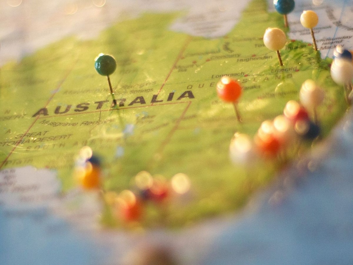 A green map of Australia with multi-coloured pins stuck in it