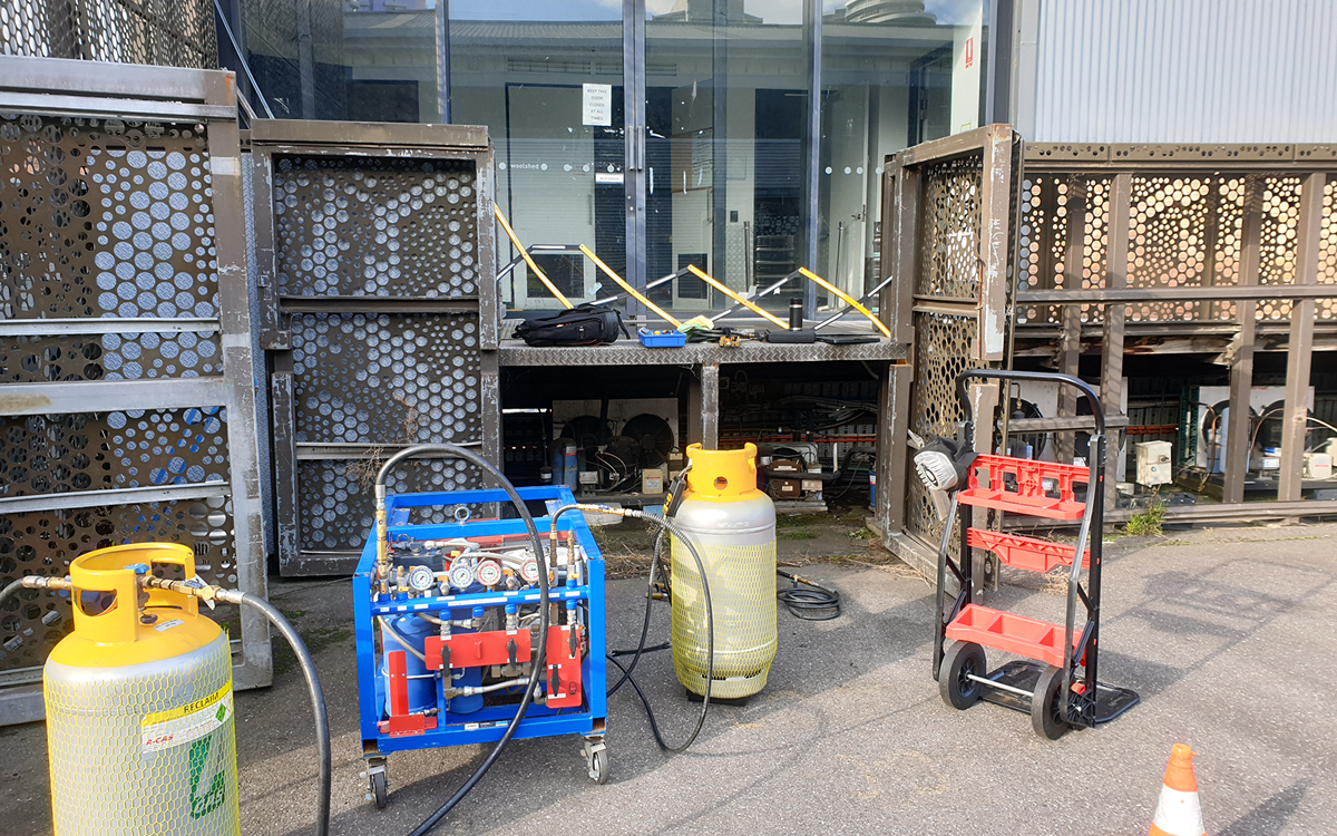Two grey recovery cylinders attached to a blue unit on a site on-site