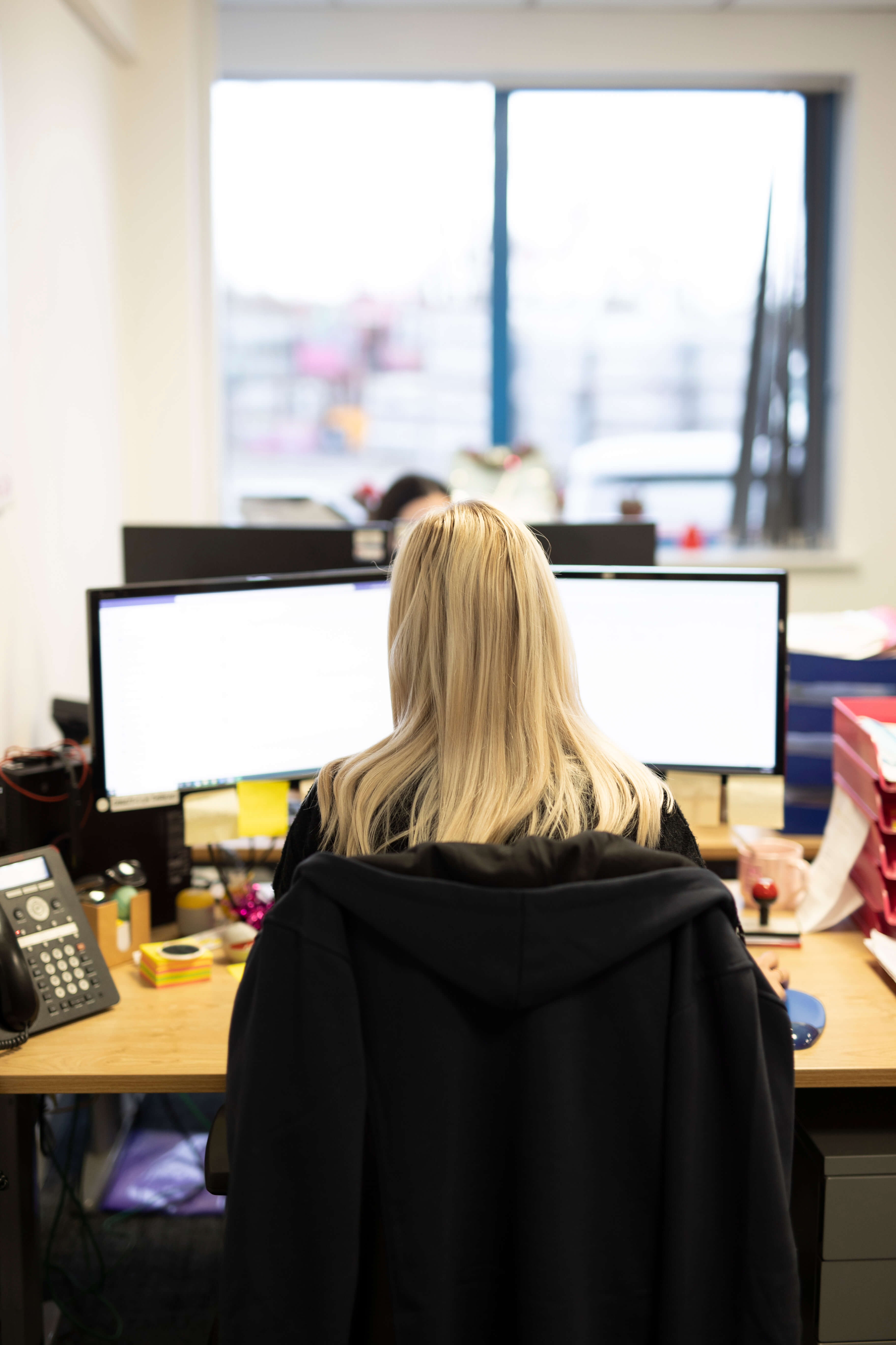 image of an office taken from behind a female looking at her screens