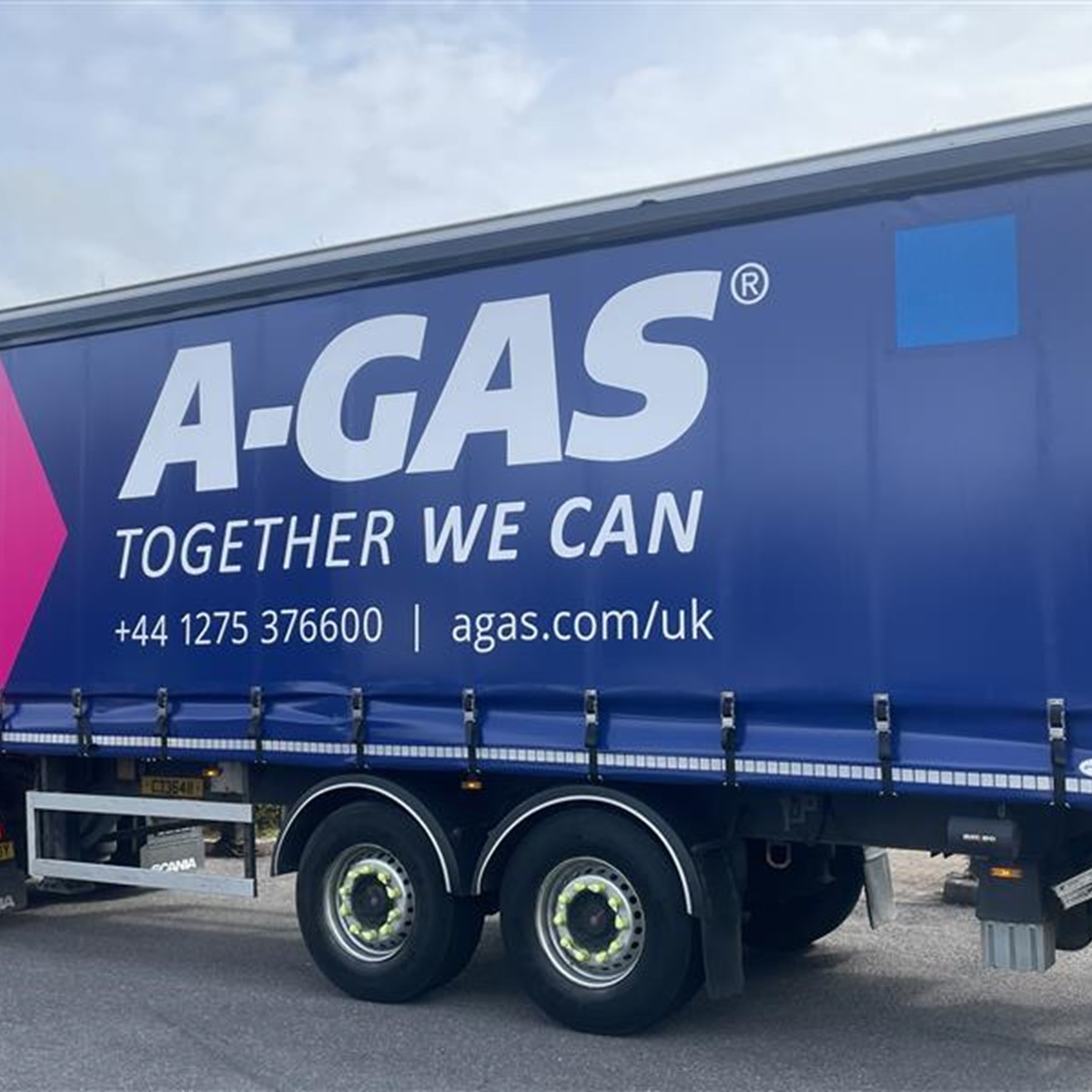 Close-up of a large lorry with the A-Gas logo in white text on a dark blue and pink background