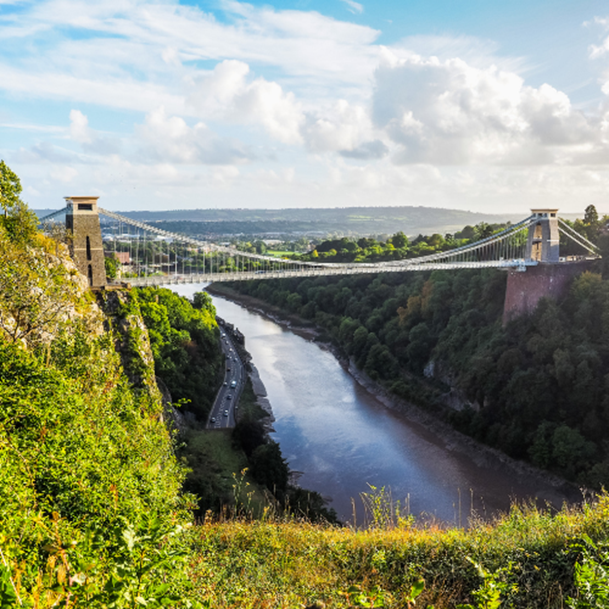 An image of Clifton Suspension Bridge with green trees and bushing around it