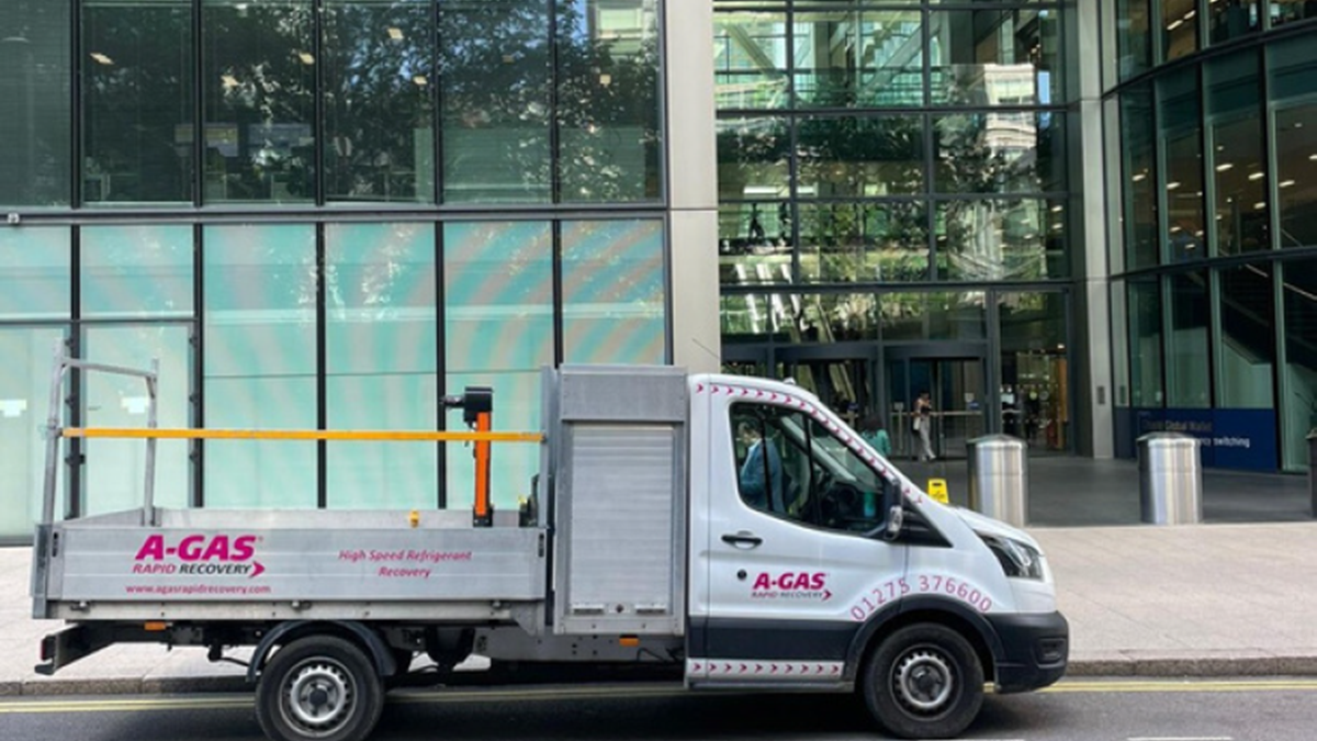 A white truck with the pink A-Gas logo on the side parked outside a green office building