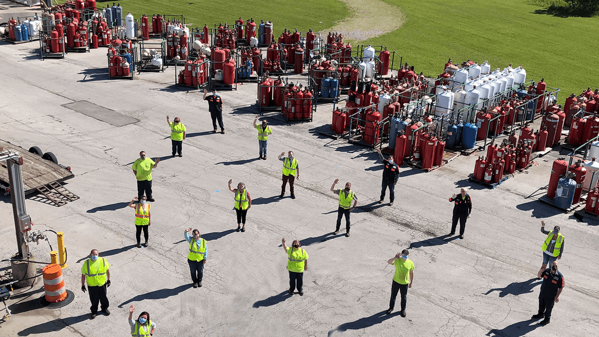 Workers lined up on site waving to the drone taking the photo