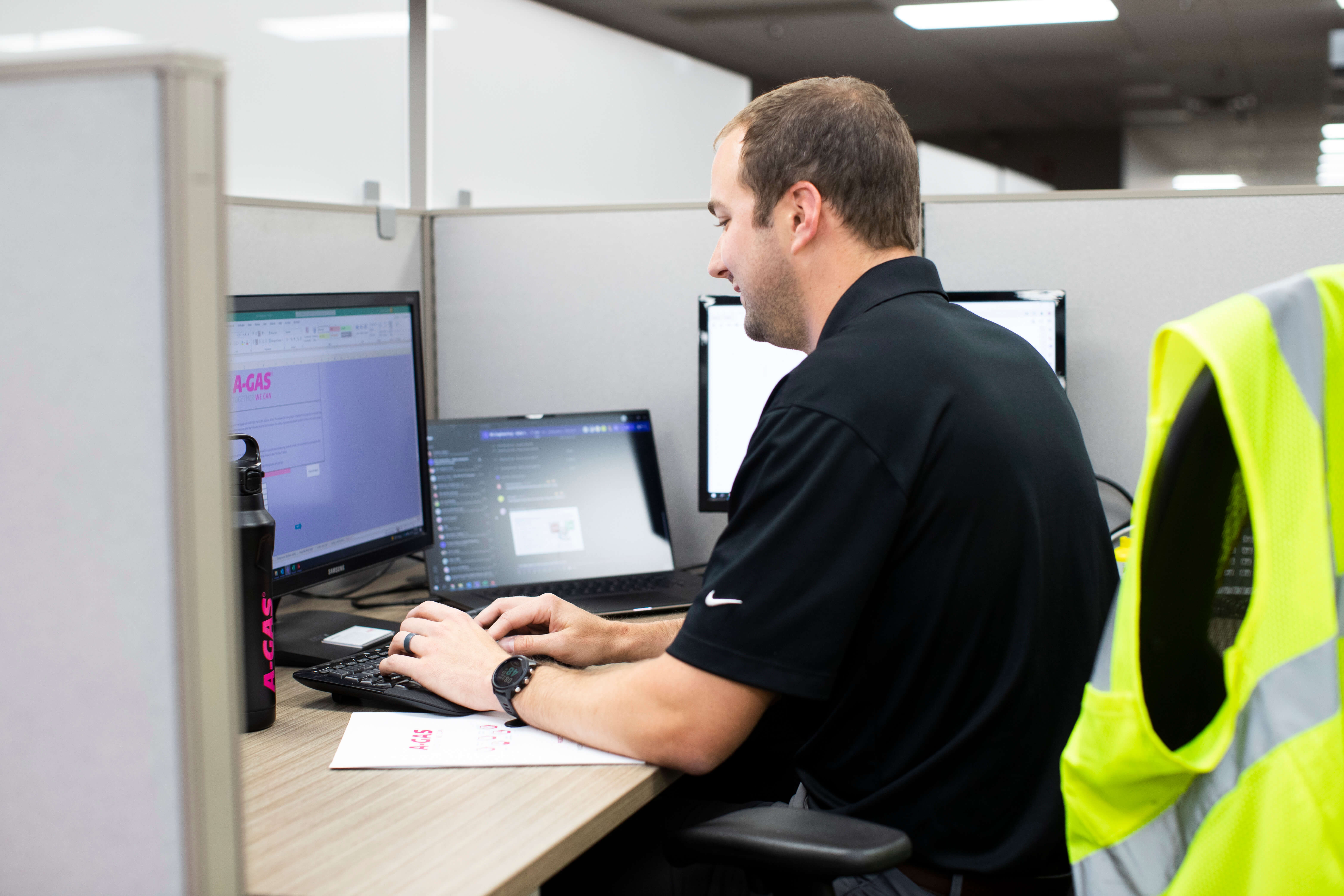 A photo taken from behind of a person sitting in an office pod using their laptop
