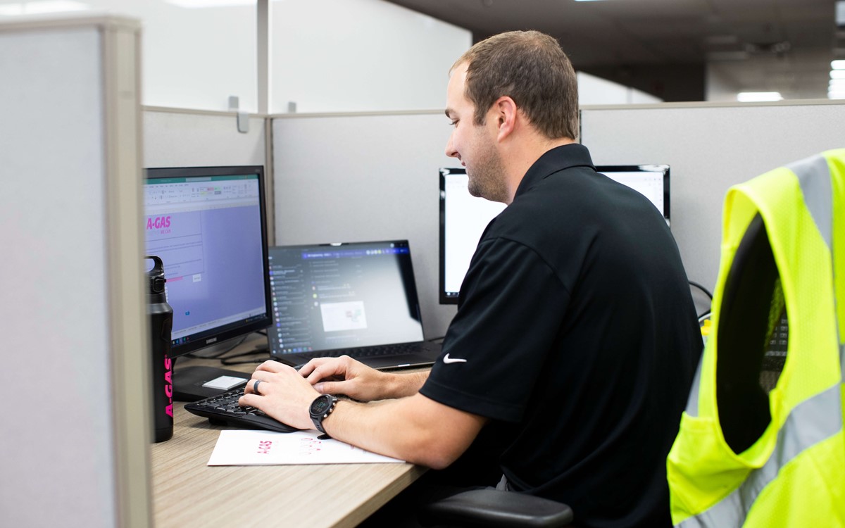 A photo taken from behind of a person sitting in an office pod using their laptop