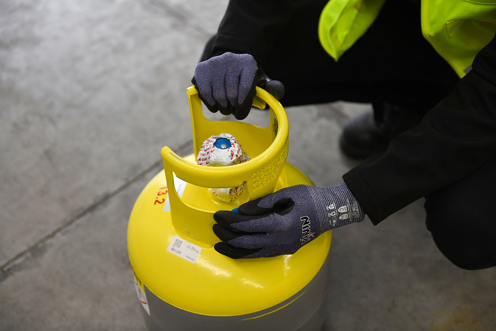 Close up of a person holding a grey cylinder with a yellow top 
