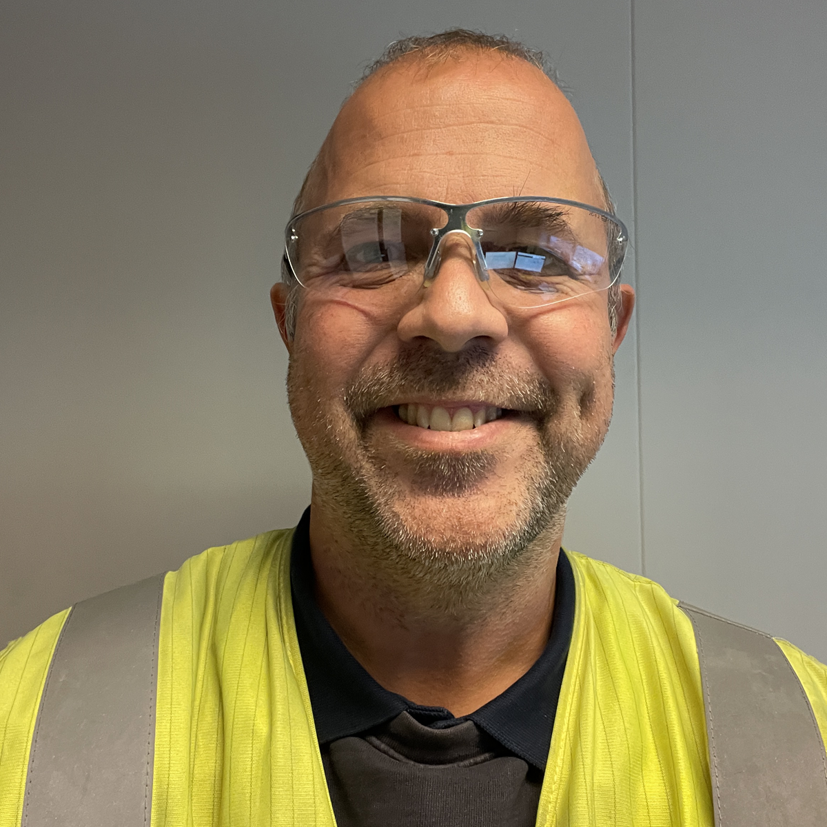 Headshot of a man smiling against a beige wall