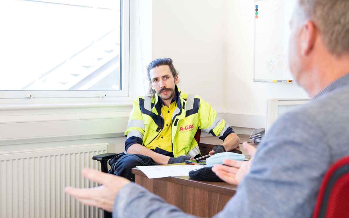 Two men sat opposite each other at a desk talking