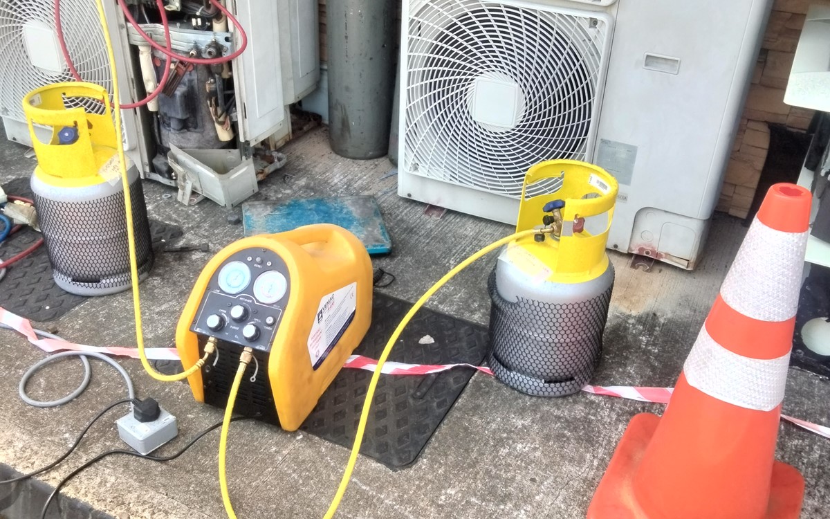 Close-up of a large grey air conditioning unit with recovery equipment and grey cylinders attached