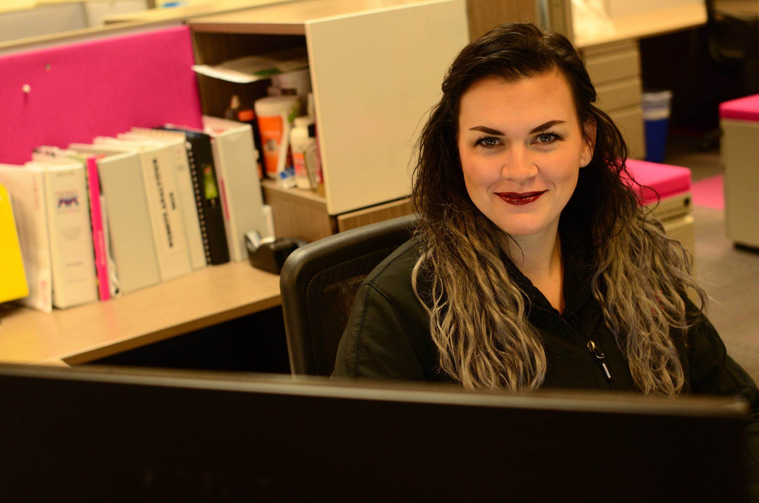 A person sat at their desk looking at the camera smiling