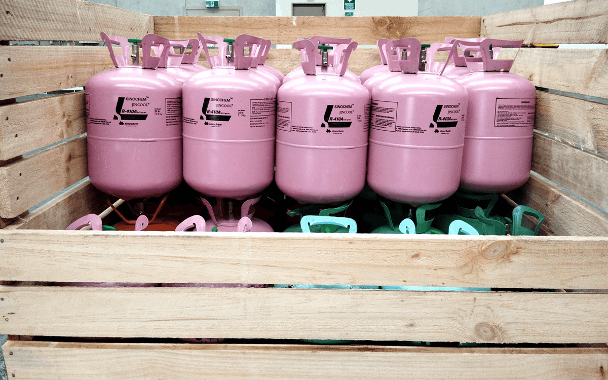 Rows of pink disposable cylinders on top of green, pink and red cylinders in a wooden crate