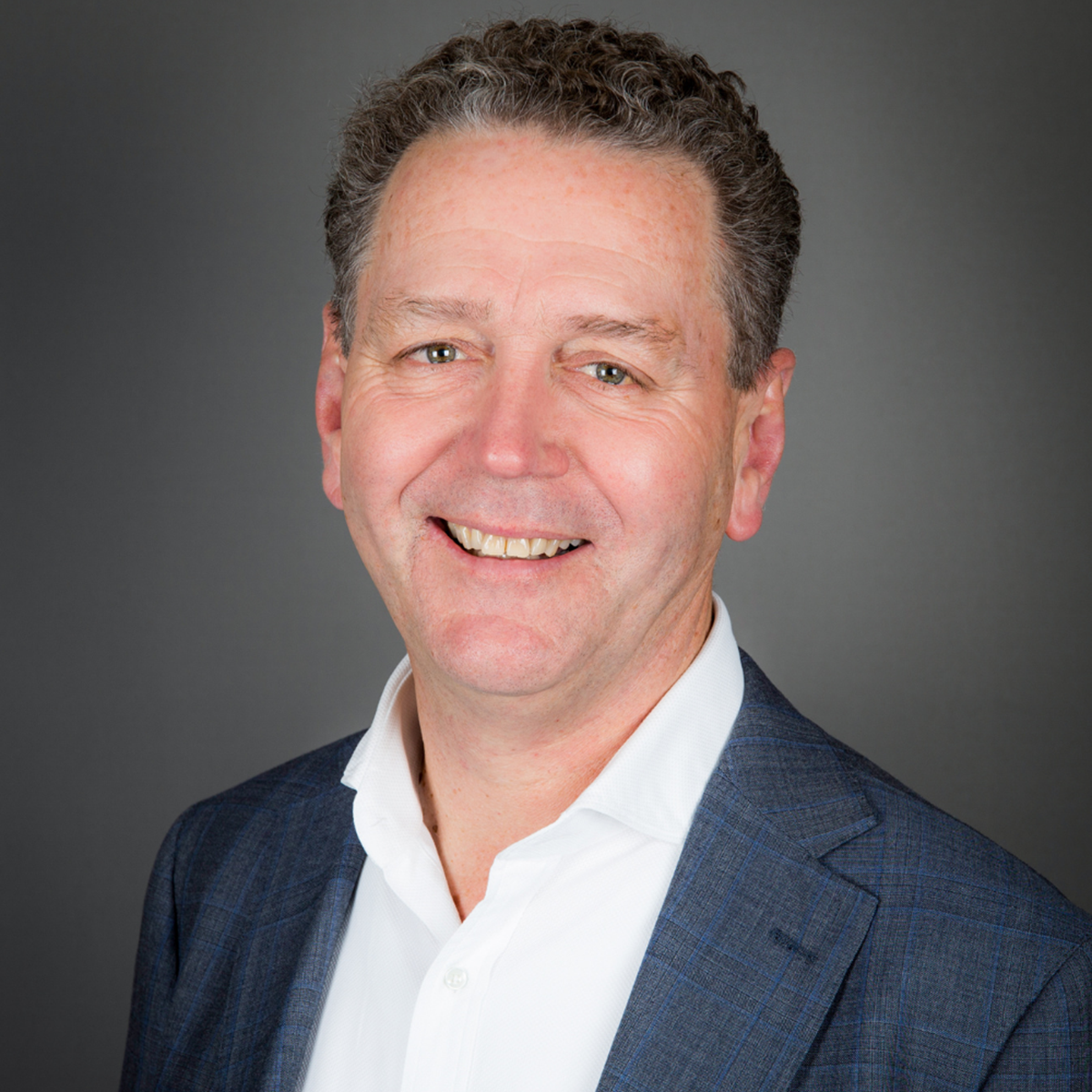 a professional headshot of a smiling company executive with a grey background