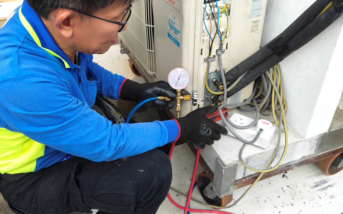 A man works with a piece of refrigerant recovery equipment