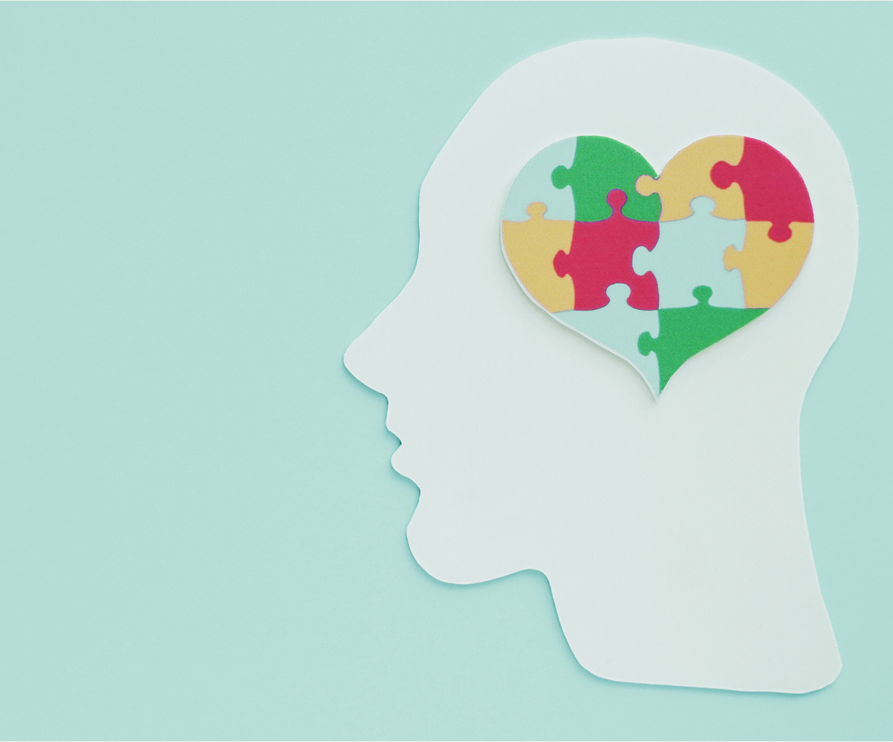 A tile featuring a cutout of a man's head with a multi-coloured love heart against a light green background 