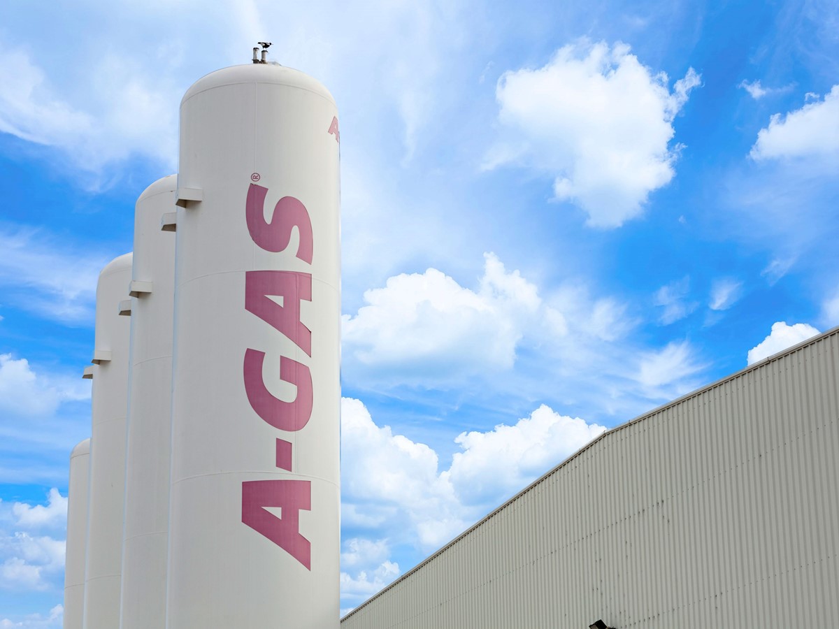 Three white separation towers with pink A-Gas logo outside a building