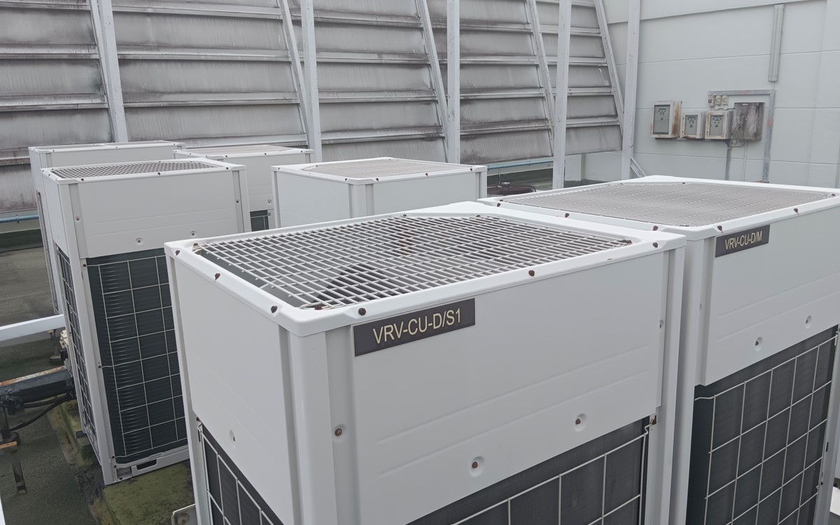 Four large white air conditioning units on a site outside