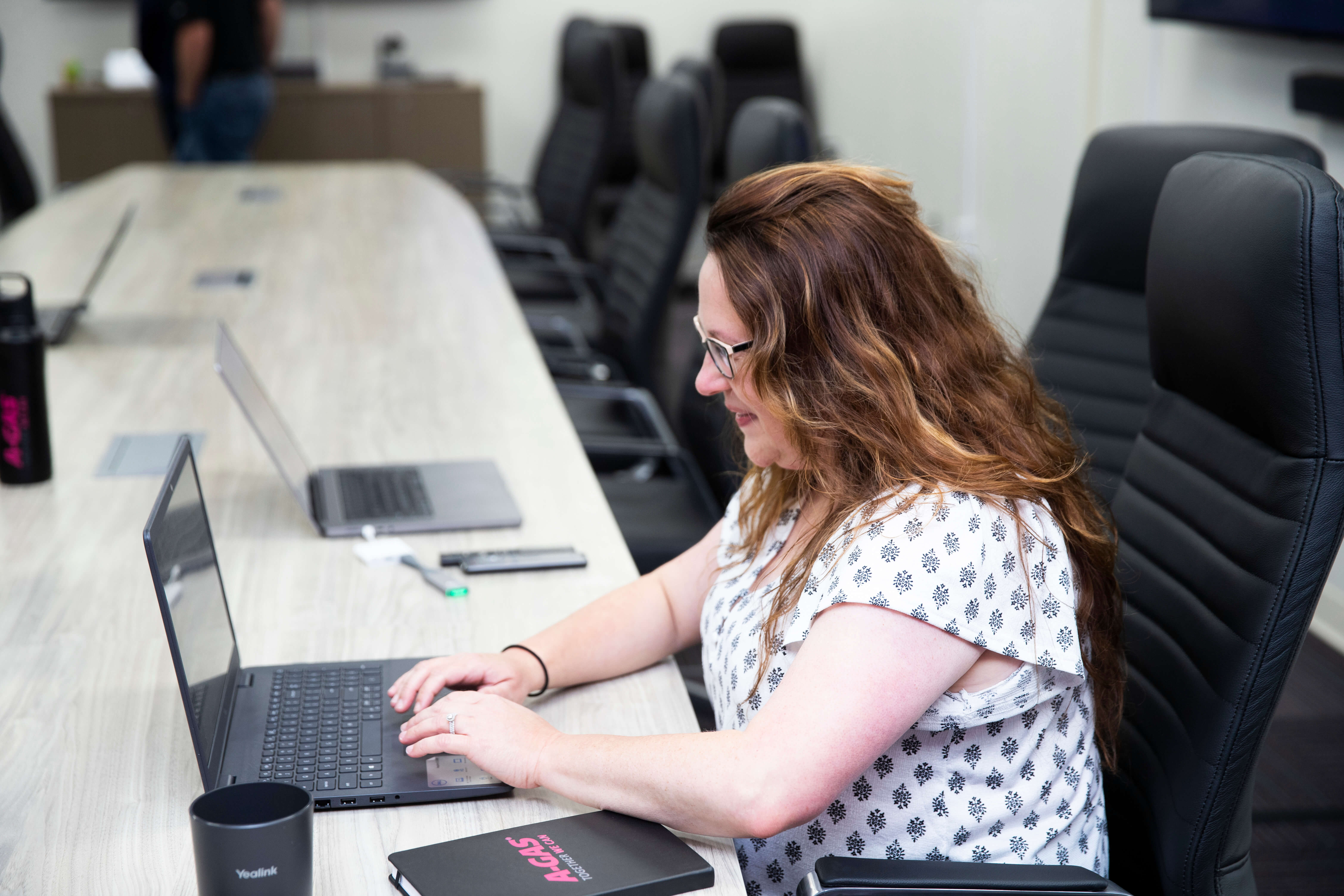 A close up of a woman sat in the boardroom working on her laptop