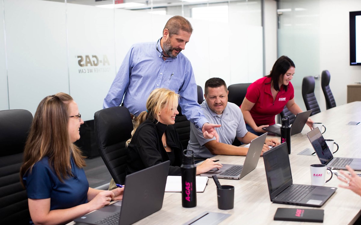 A group of men and women smiling while working together in an office