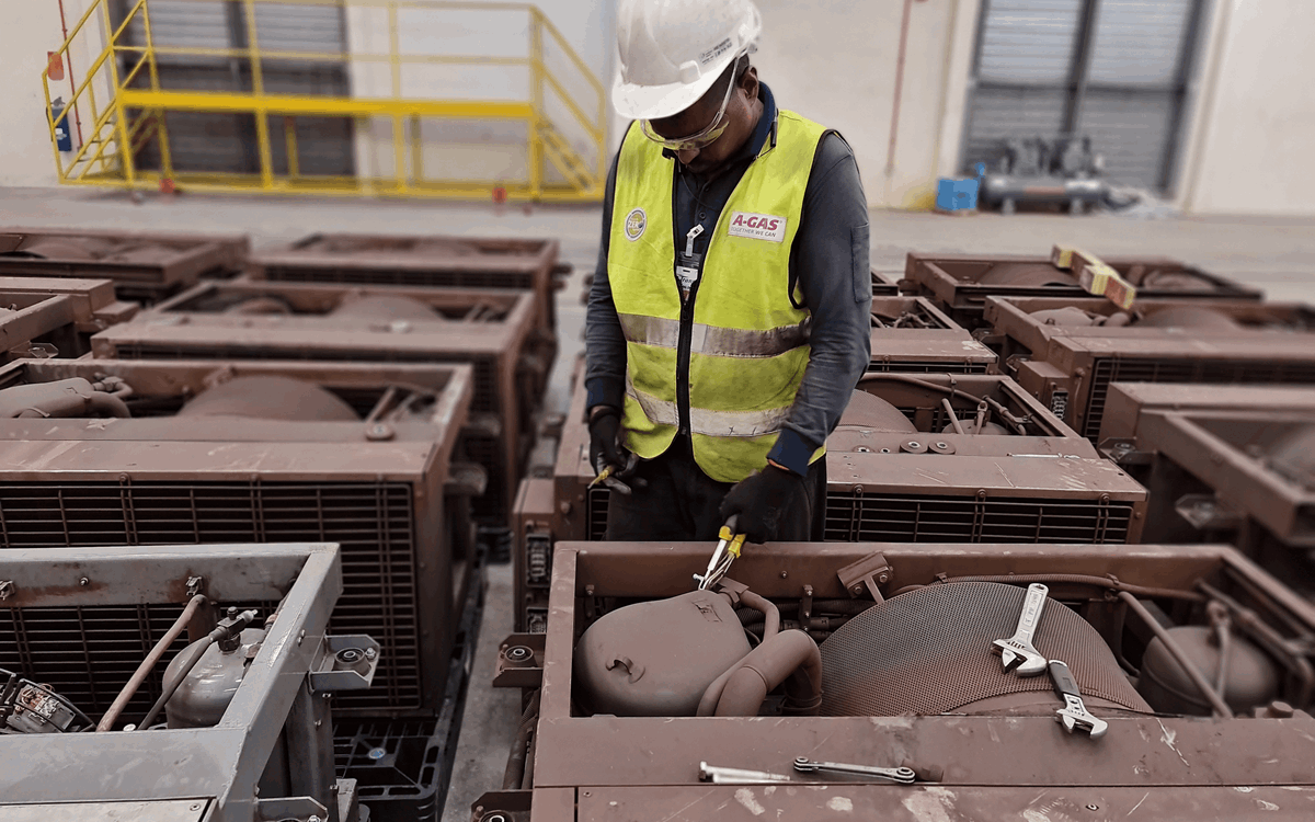 A man in a yellow high-vis jacket and hard hat working on an air conditioning unit