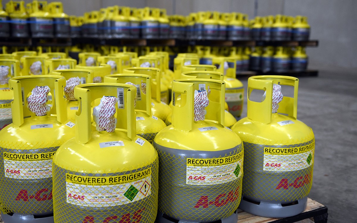 A close-up of grey cylinders with yellow tops on a palette in a warehouse