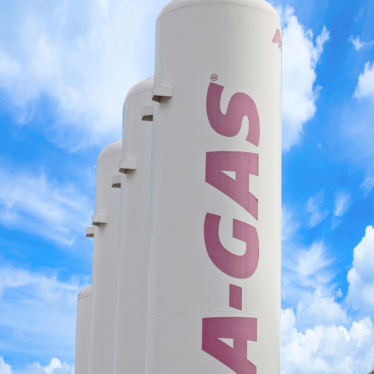 Four white separation towers with pink A-Gas logo outside a building