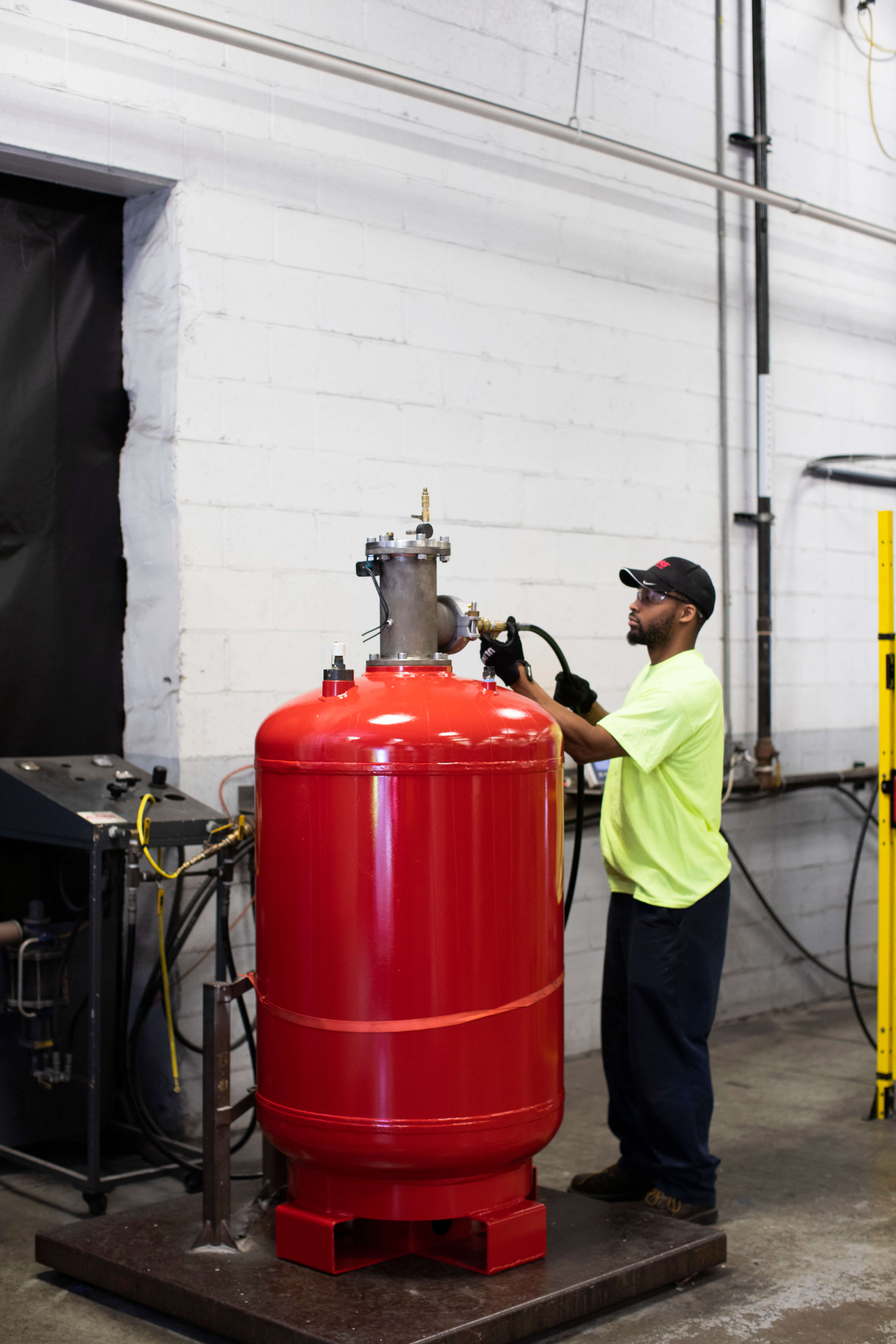 A person working with a large red half ton cylinder, the cylinder is taller than him