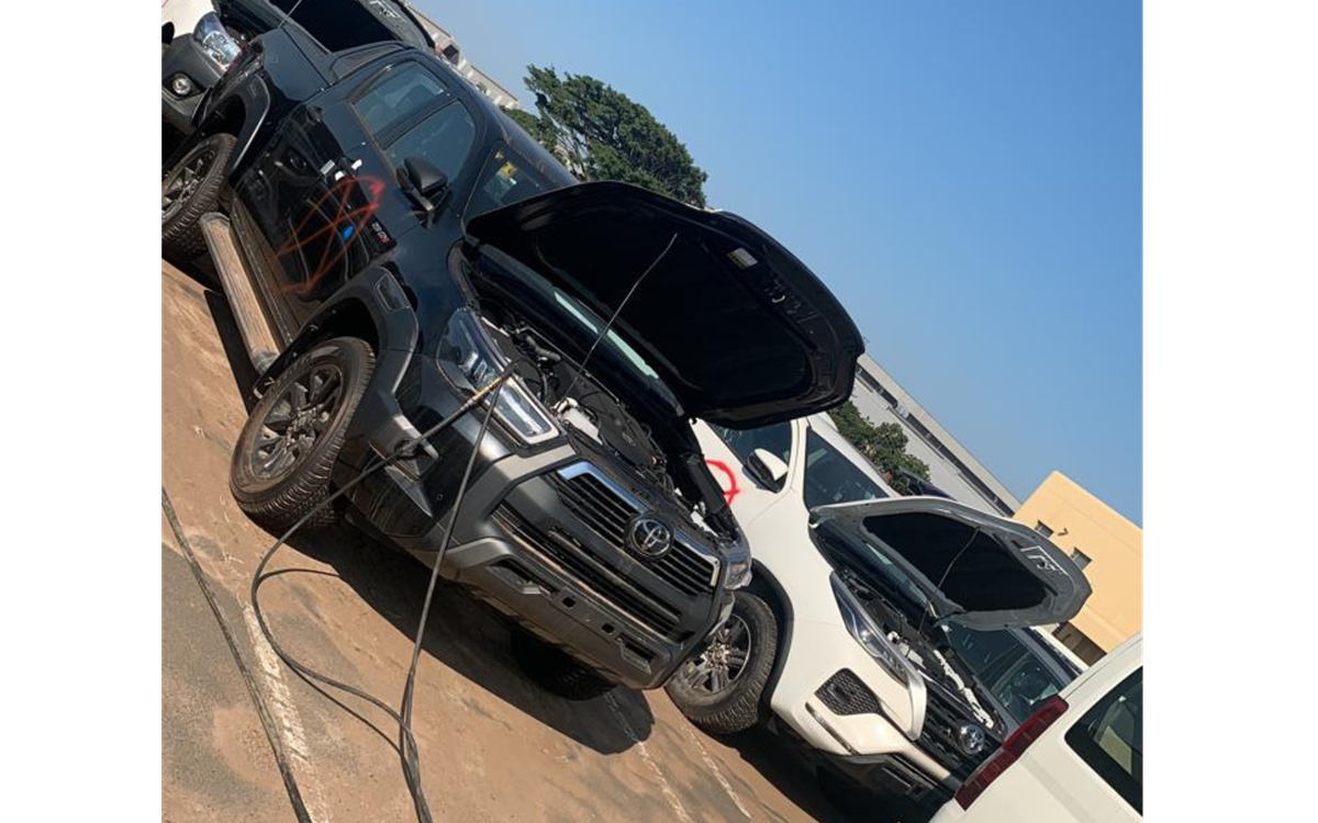 A black car with its bonnet open with a recovery hose in its engine