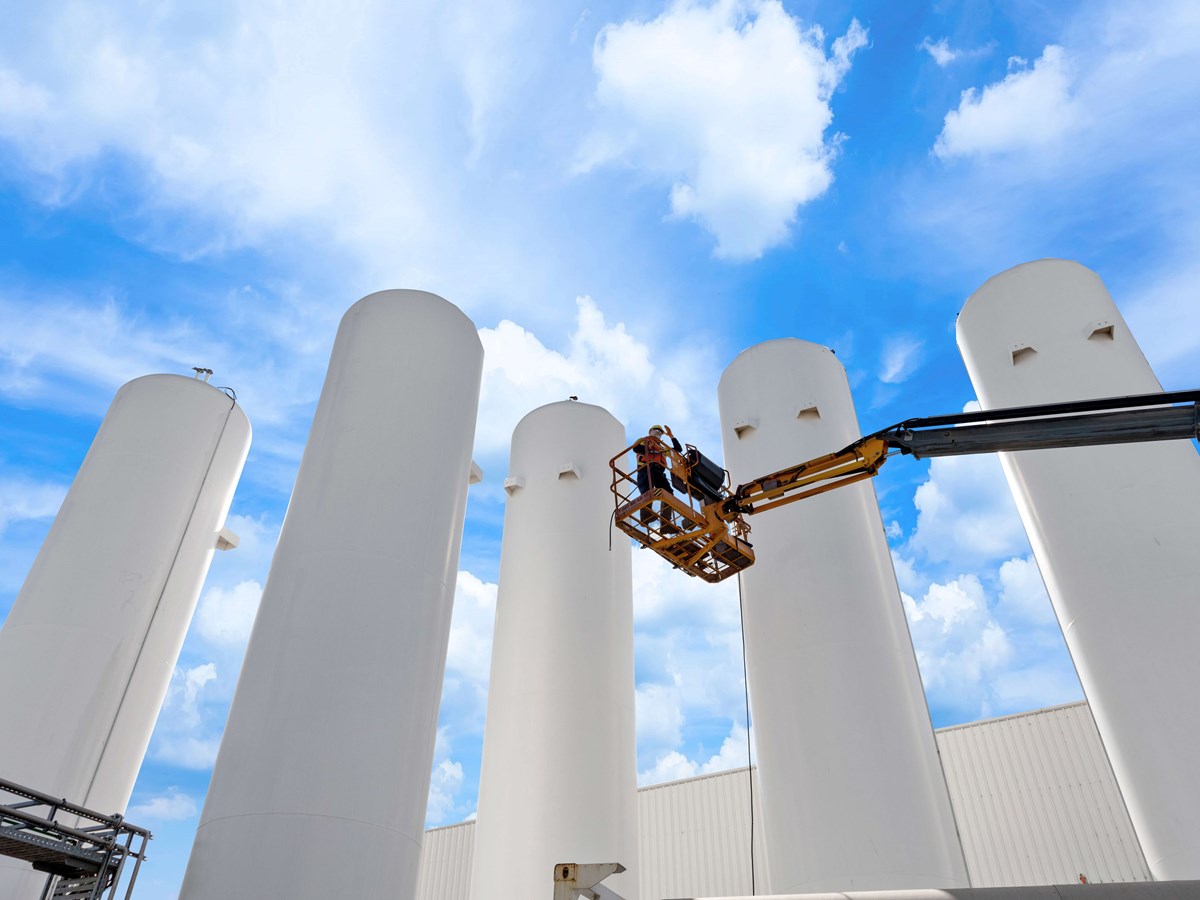 Five white recovery separator towers with an operator on a platform