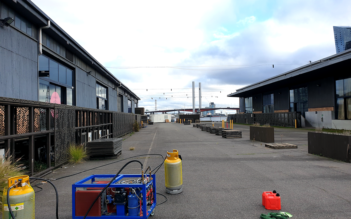 Wide shot of a site with two grey cylinders attached to a blue recovery unit in the foreground