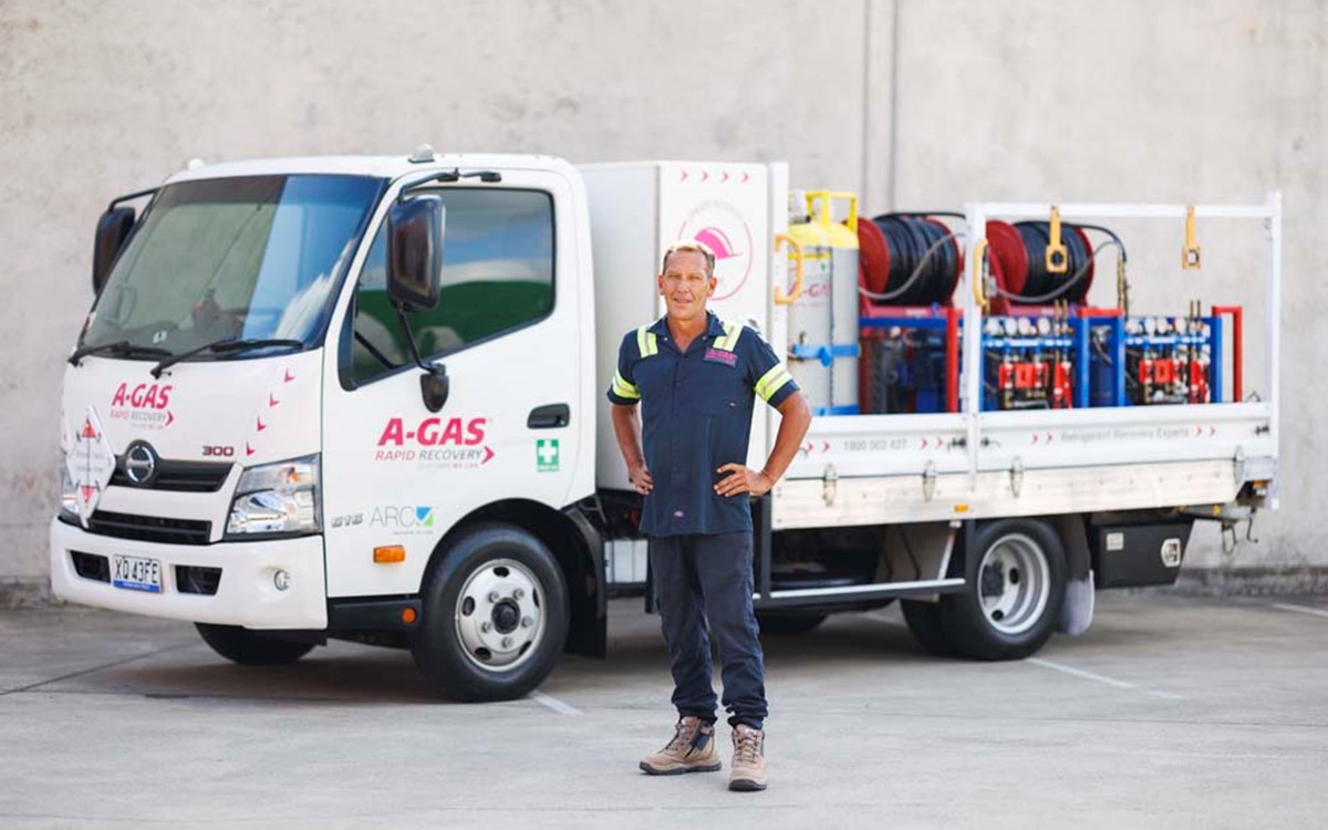 Man standing in front of a white truck with hands on hips while looking at the camera