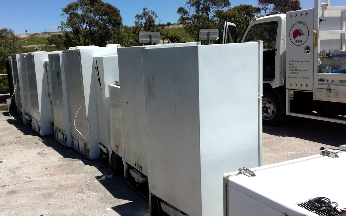 A row of disused fridges from behind in a scrapyard