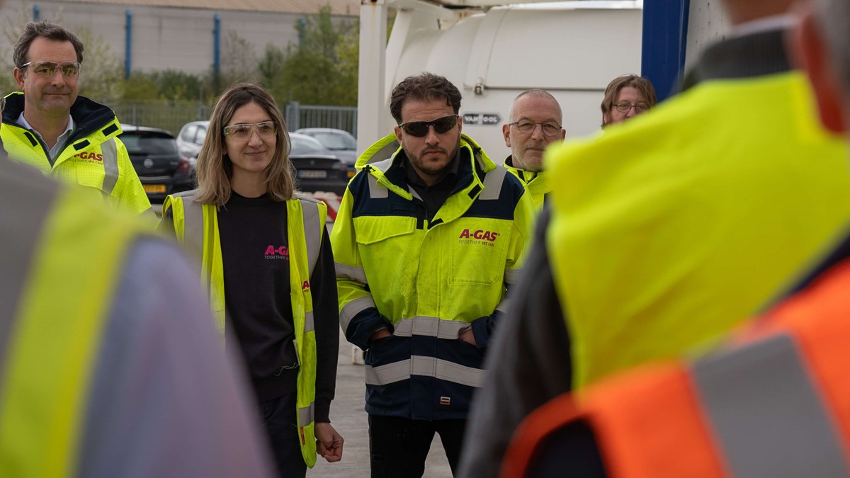 A group of men and women in yellow hi-vis jackets talking outside