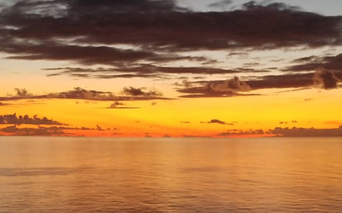 A wide shot of a landscape with a body of water and the Bahamas on the horizon
