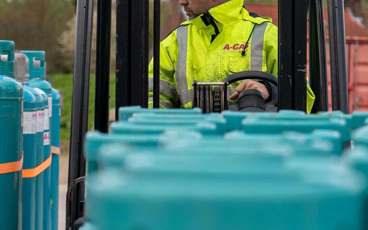 A man in a yellow high-vis jacket driving a blue forklift truck