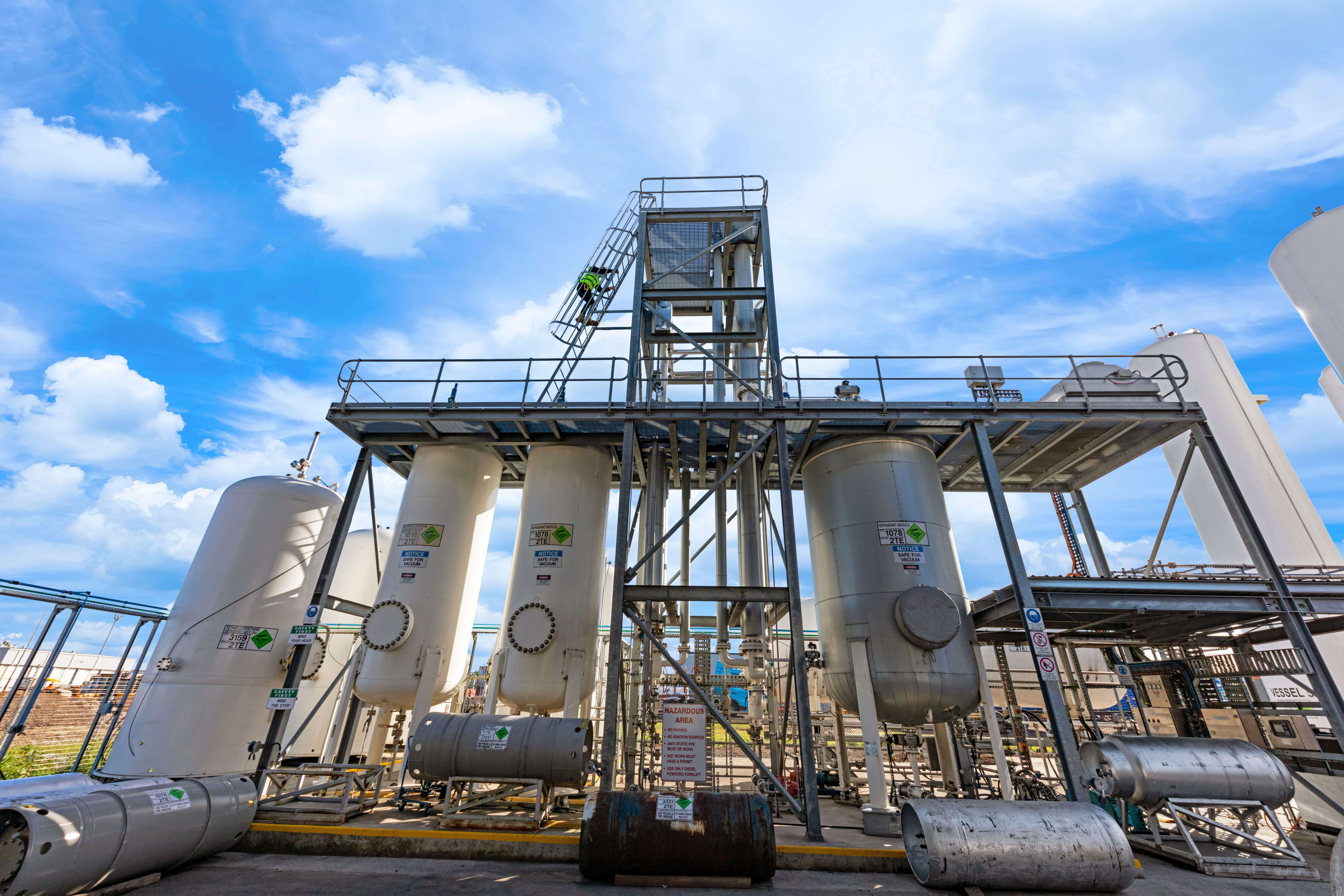 White separation towers surrounded by metal scaffolding with technician climbing a ladder 