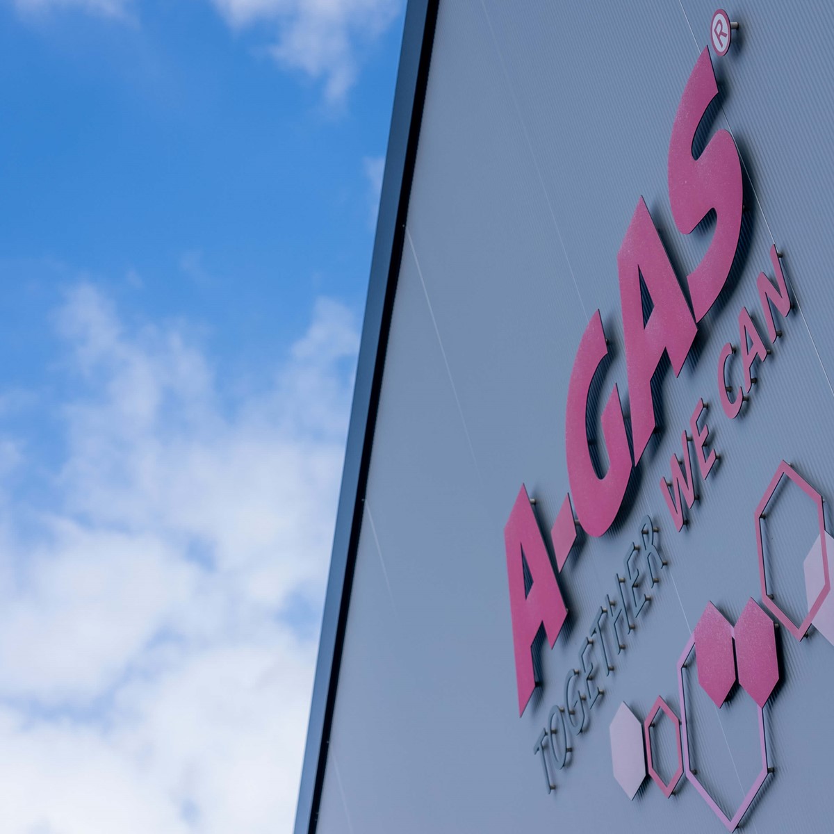 The pink A-Gas logo with hexagons on the side of a building