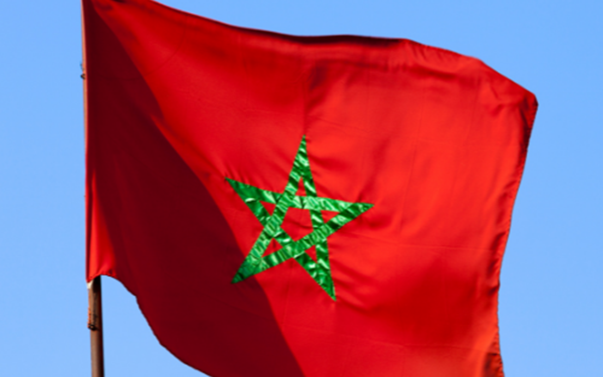 A red flag with a green star at the centre outside against a blue sky