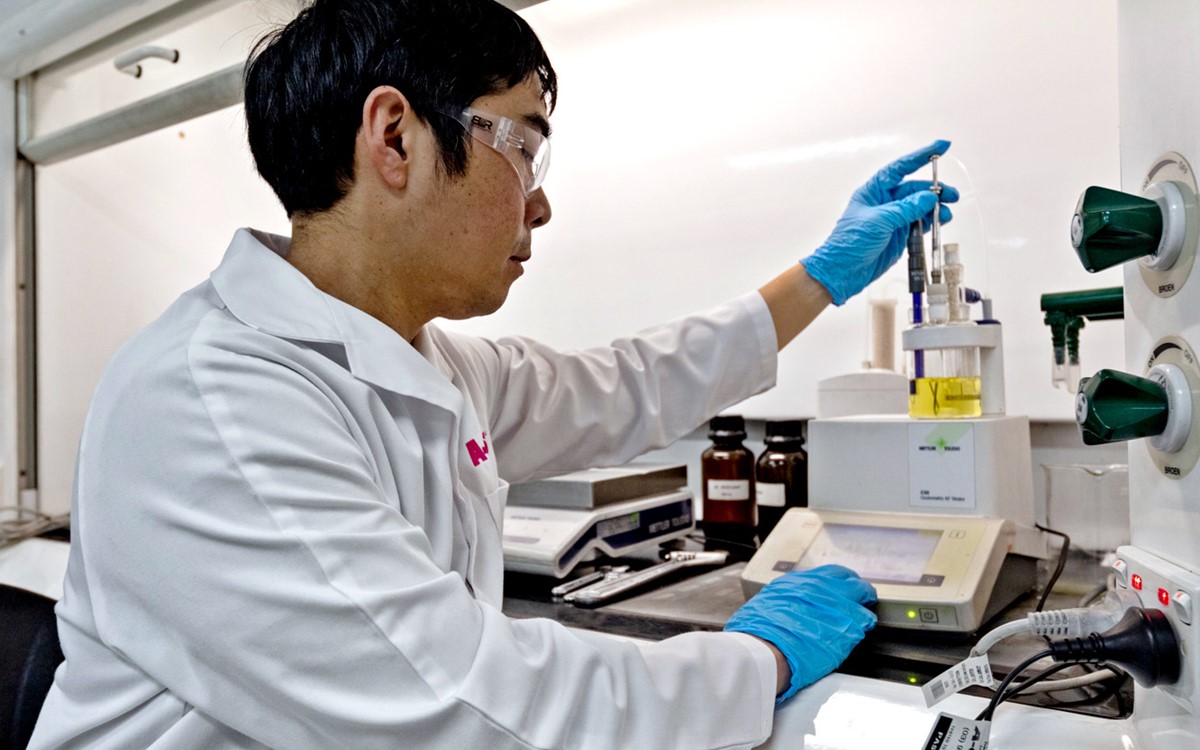 A lab technician in a white coat working with testing equipment