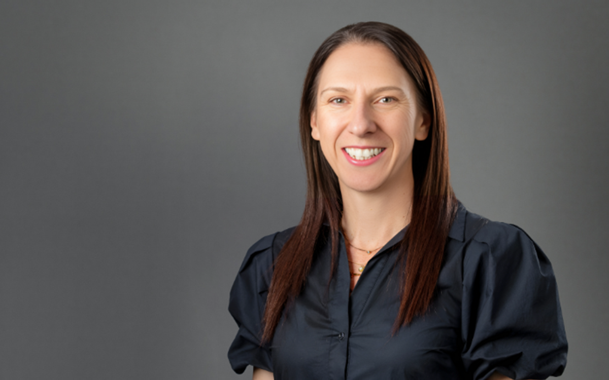 Headshot of a smiling woman against a dark grey backdrop