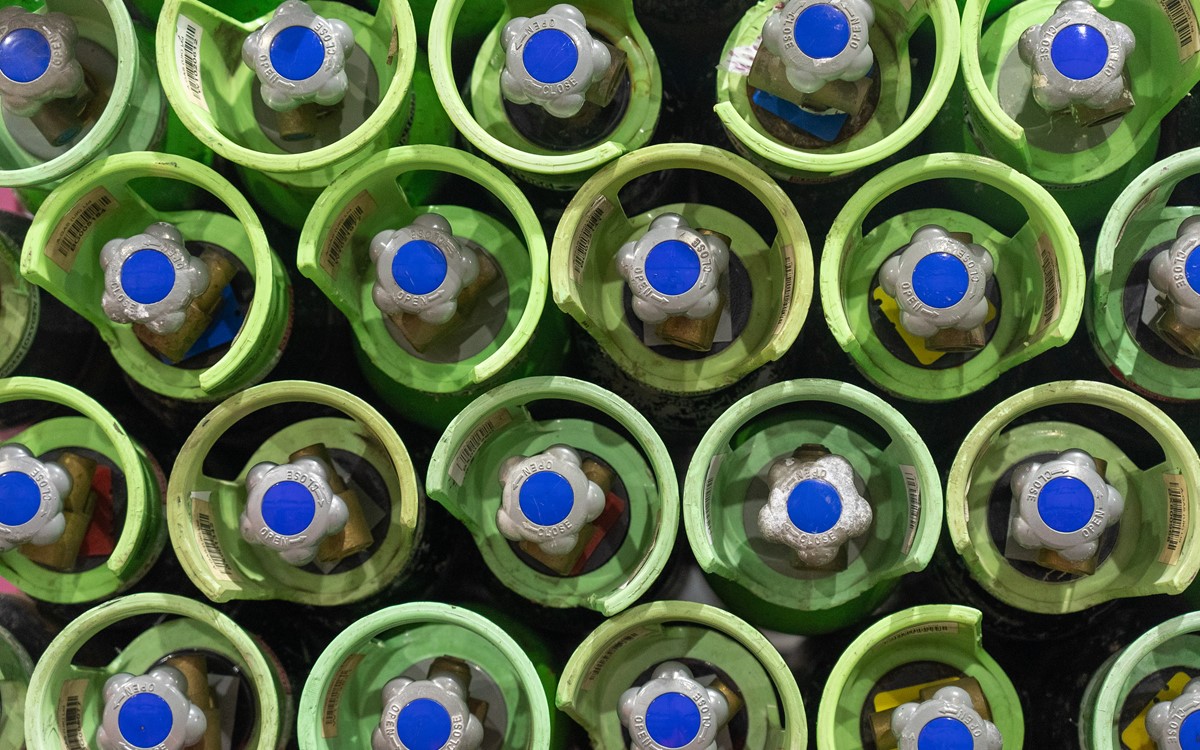 Rows of cylinders with green tops and blue valves from above