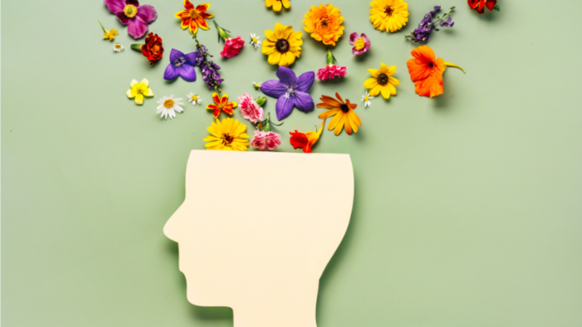 A banner image with a beige outline of a head with flowers coming out the top on a light green background