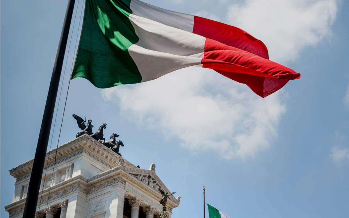 The green, white and red flag of Italian in front of a white building from below