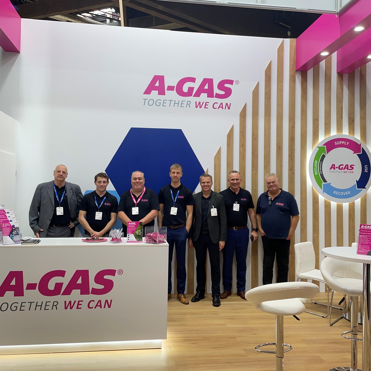 A group of men standing at an A-Gas stall in a tradeshow hall
