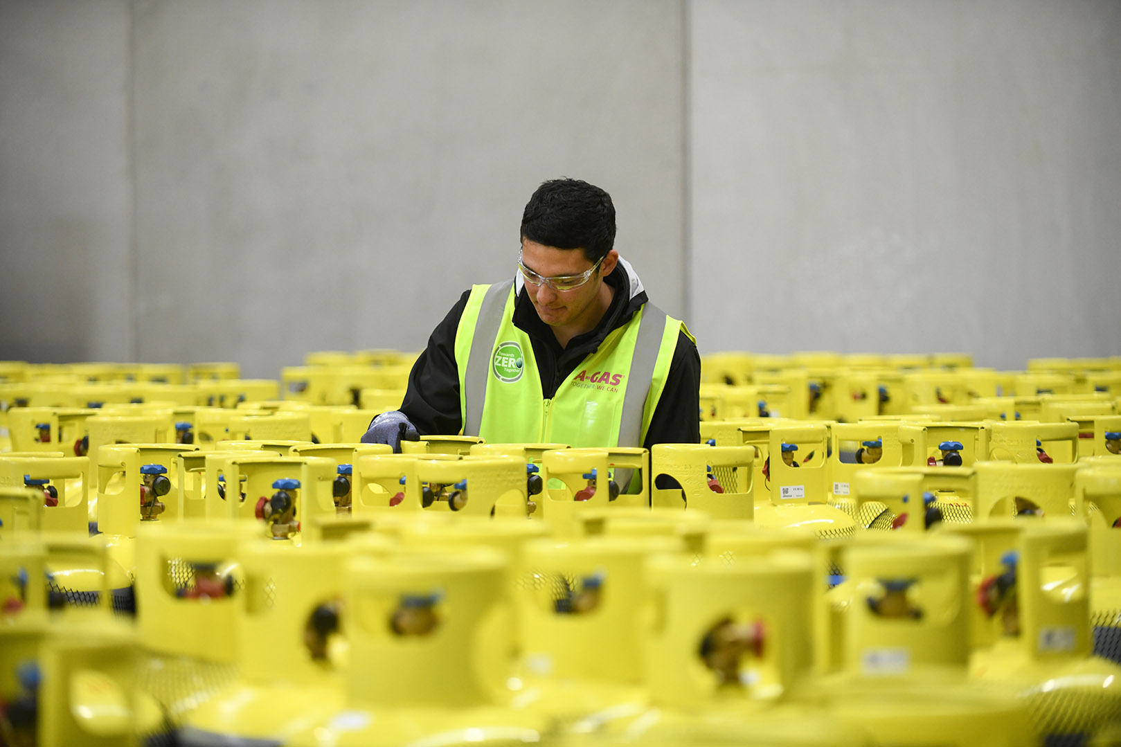 A man working in the middle of stacked cylinders in a warehouse 