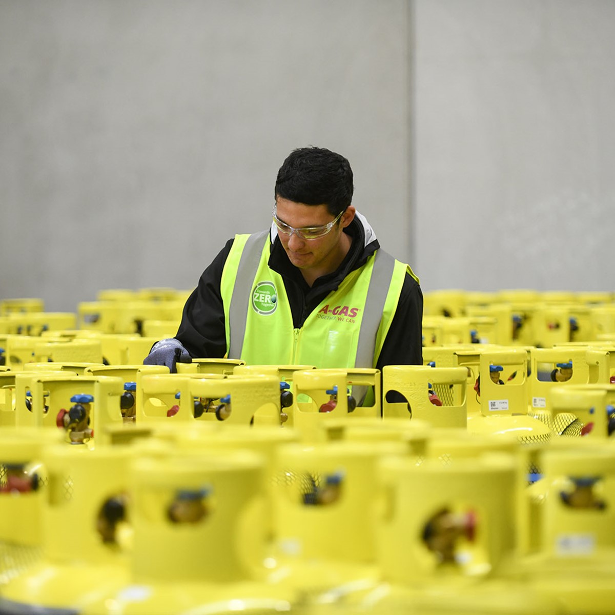 A man working in the middle of stacked cylinders in a warehouse