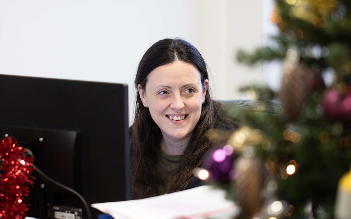 Person working at the computer with a Christmas tree