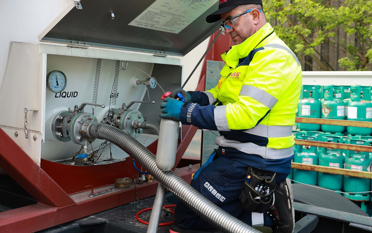 Man in a yellow high-vis jacket working on-site with refrigerant recovery equipment